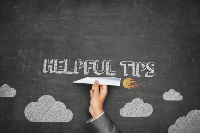 Helpful tips concept on black blackboard with businessman hand holding paper plane
