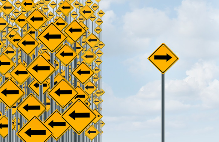 Direction individuality and independent thinking concept as a group of directional arrow traffic signs with one individual pointing in the opposite way as a business icon for innovative solution.